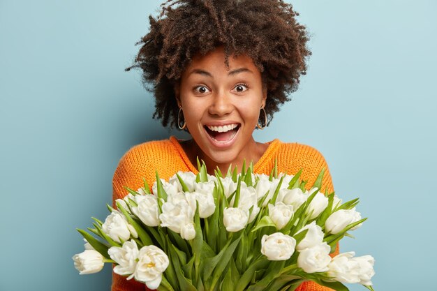 Young woman with Afro haircut holding bouquet of white flowers