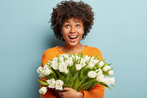 Giovane donna con taglio di capelli afro holding bouquet di fiori bianchi