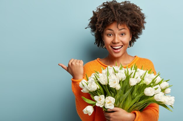 Young woman with Afro haircut holding bouquet of white flowers