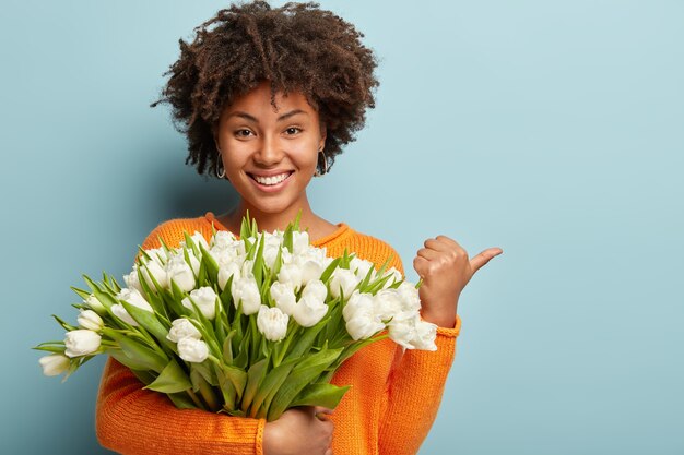 Young woman with Afro haircut holding bouquet of white flowers