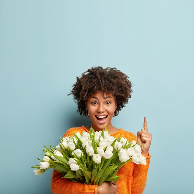 Young woman with Afro haircut holding bouquet of white flowers