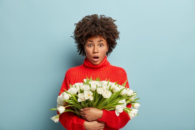 Young woman with Afro haircut holding bouquet of white flowers