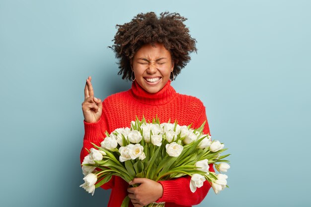 白い花の花束を保持しているアフロの散髪を持つ若い女性