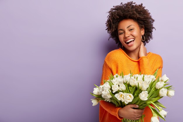 Young woman with Afro haircut holding bouquet of white flowers