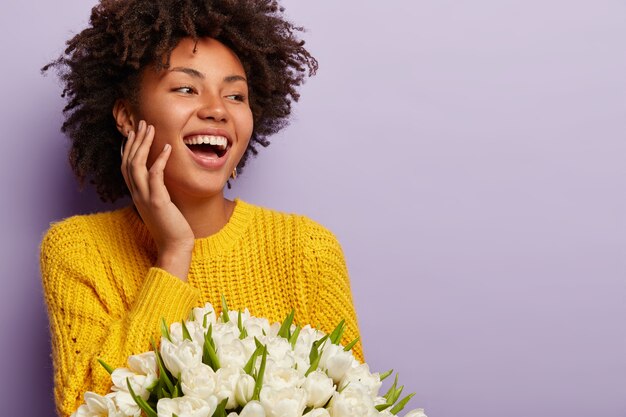 Young woman with Afro haircut holding bouquet of white flowers