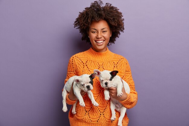 Young woman with Afro haircut holding puppies