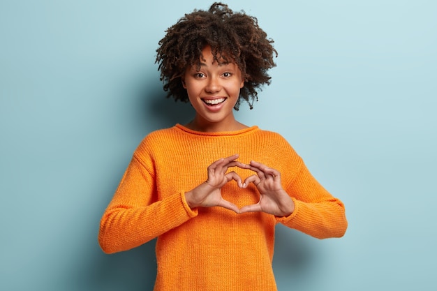 Free photo young woman with afro haircut wearing orange jumper