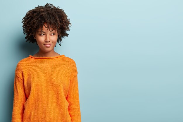 Young woman with Afro haircut wearing orange jumper