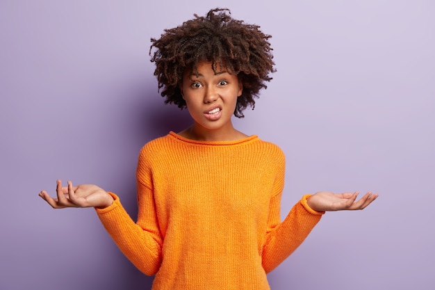 Giovane donna con taglio di capelli afro che indossa un maglione arancione