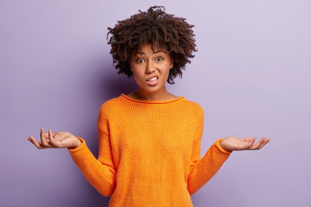 Young woman with Afro haircut wearing orange sweater