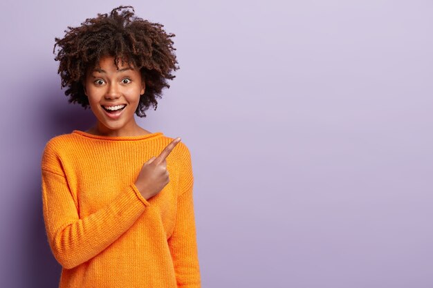 Young woman with Afro haircut wearing orange sweater