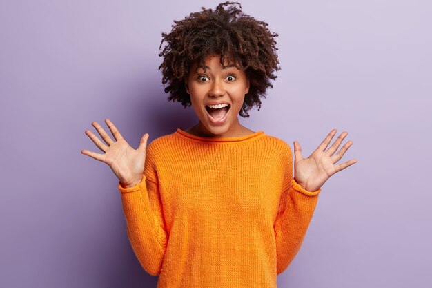 Young woman with Afro haircut wearing orange sweater