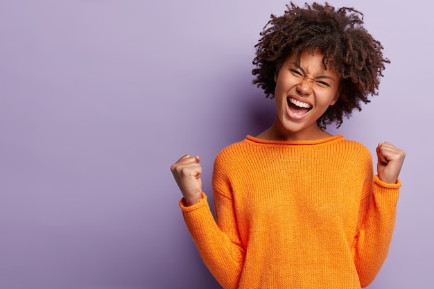 Foto gratuita giovane donna con taglio di capelli afro che indossa un maglione arancione