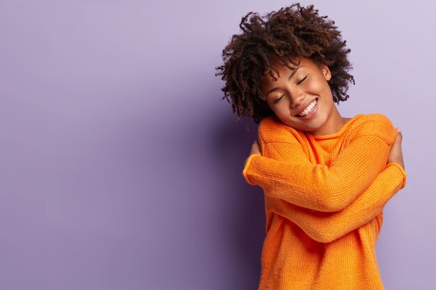 オレンジ色のセーターを着てアフロヘアカットの若い女性