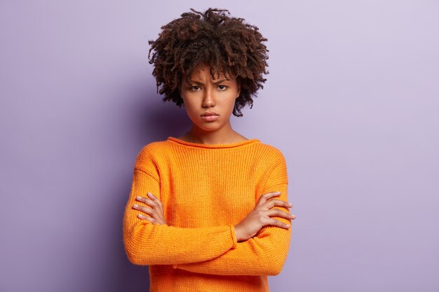 주황색 스웨터를 입고 아프로 머리를 가진 젊은 여자