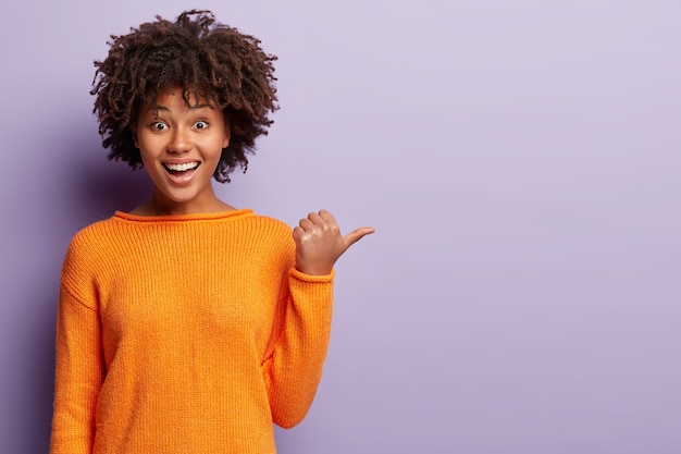 オレンジ色のセーターを着てアフロヘアカットの若い女性