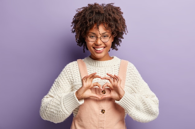 Free photo young woman with afro haircut wearing overalls and sweater