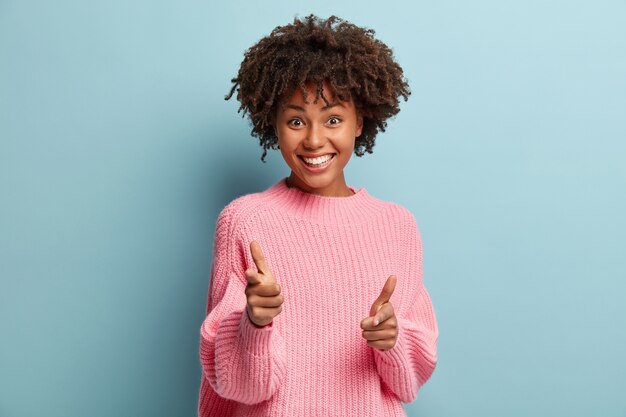 ピンクのセーターを着てアフロヘアカットの若い女性