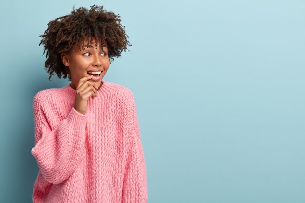 Young woman with Afro haircut wearing pink sweater