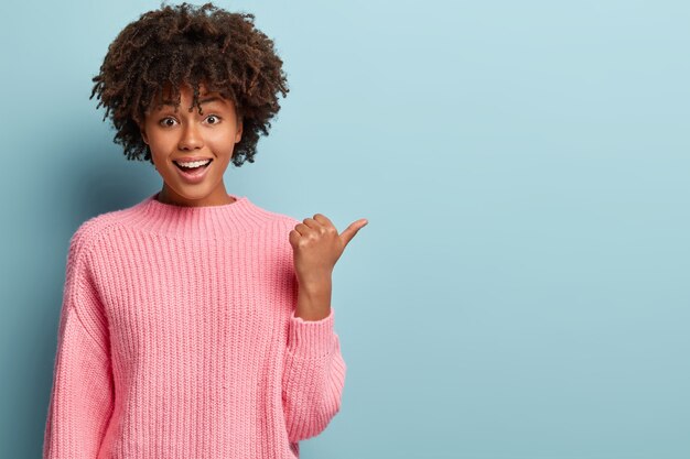 ピンクのセーターを着てアフロヘアカットの若い女性