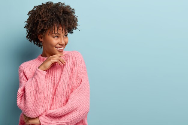 ピンクのセーターを着てアフロヘアカットの若い女性