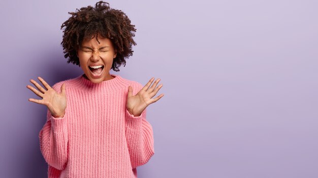 ピンクのセーターを着てアフロヘアカットの若い女性