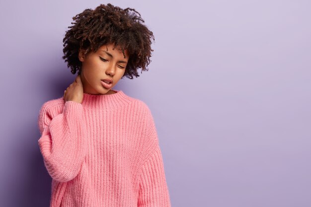Бесплатное фото Молодая женщина с афро-стрижкой в розовом свитере
