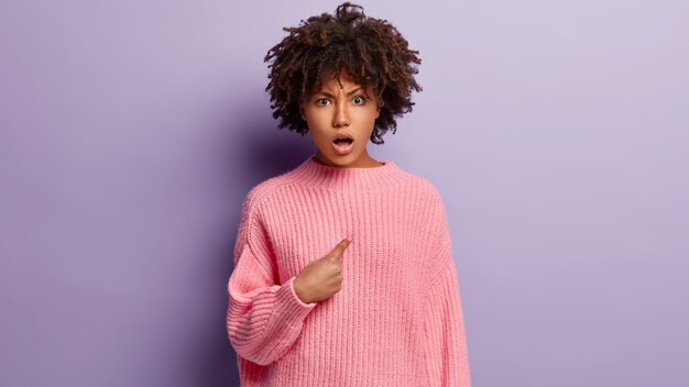 ピンクのセーターを着てアフロヘアカットの若い女性