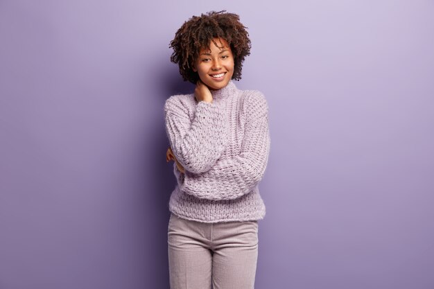 Молодая женщина с афро-стрижкой в фиолетовом свитере
