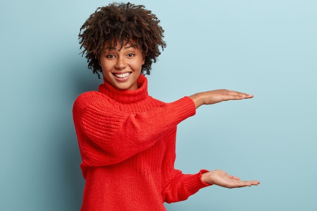 赤いセーターを着てアフロヘアカットの若い女性