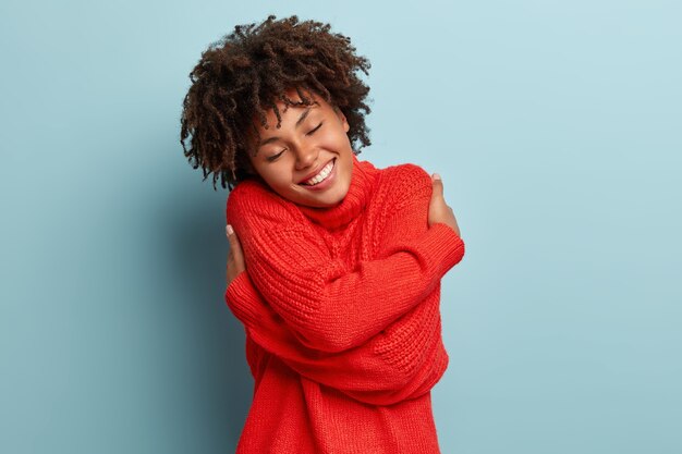 赤いセーターを着てアフロヘアカットの若い女性