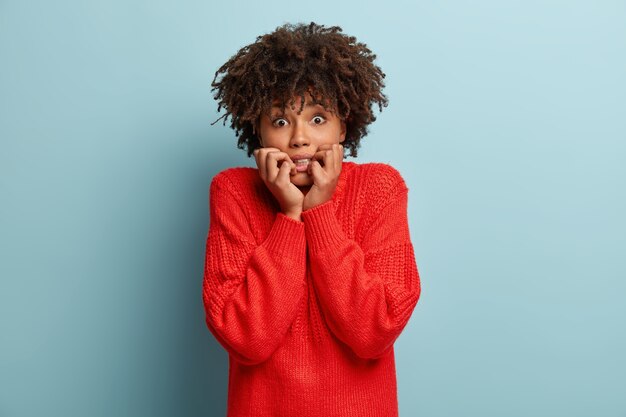 赤いセーターを着てアフロヘアカットの若い女性