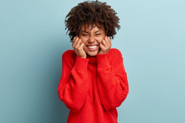 赤いセーターを着てアフロヘアカットの若い女性