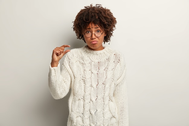 Giovane donna con taglio di capelli afro che indossa un maglione bianco