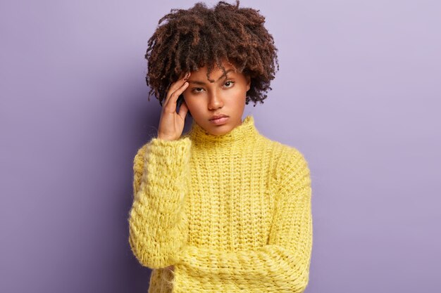 黄色のセーターを着てアフロヘアカットの若い女性