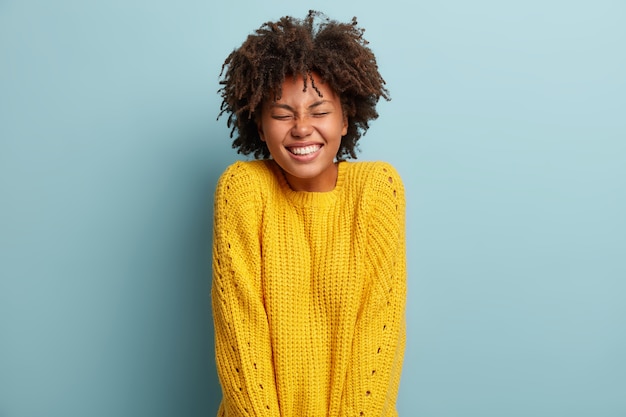 Foto gratuita giovane donna con taglio di capelli afro che indossa un maglione giallo