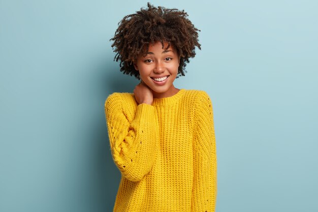 黄色のセーターを着てアフロヘアカットの若い女性