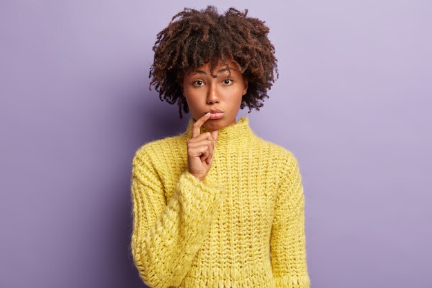 黄色のセーターを着てアフロヘアカットの若い女性