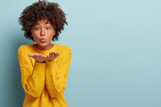 Foto gratuita giovane donna con taglio di capelli afro che indossa un maglione giallo