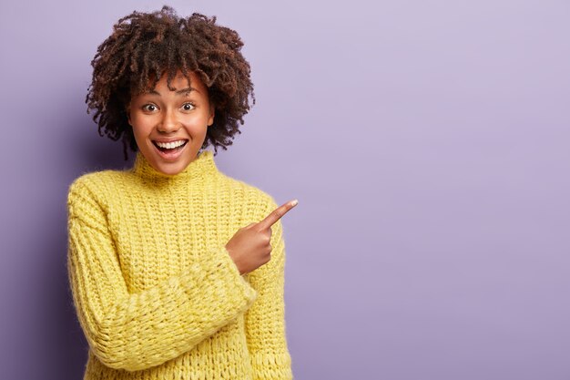 黄色のセーターを着てアフロヘアカットの若い女性