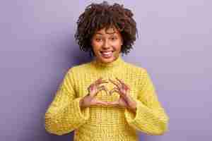 Free photo young woman with afro haircut wearing yellow sweater