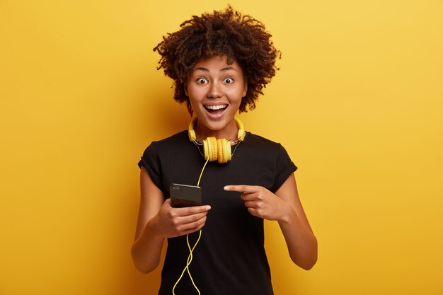 Young woman with Afro haircut with yellow headphones