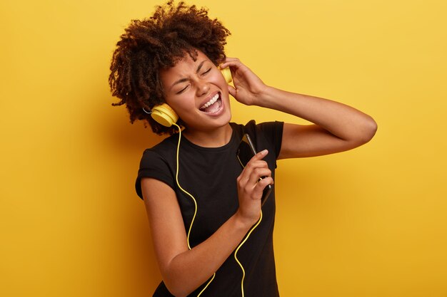 Young woman with Afro haircut with yellow headphones