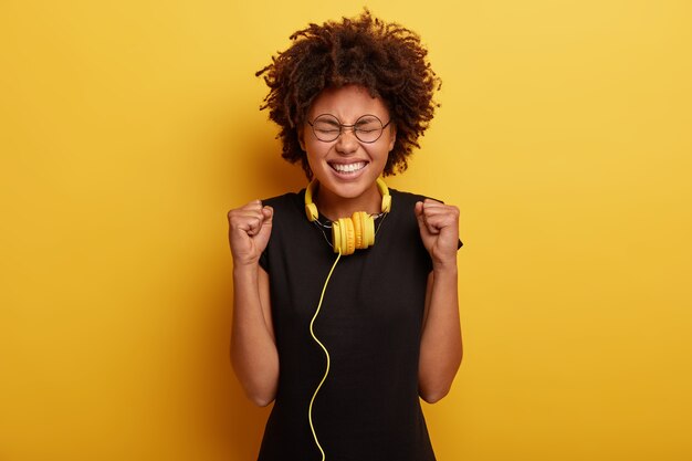 Young woman with Afro haircut and yellow headphones
