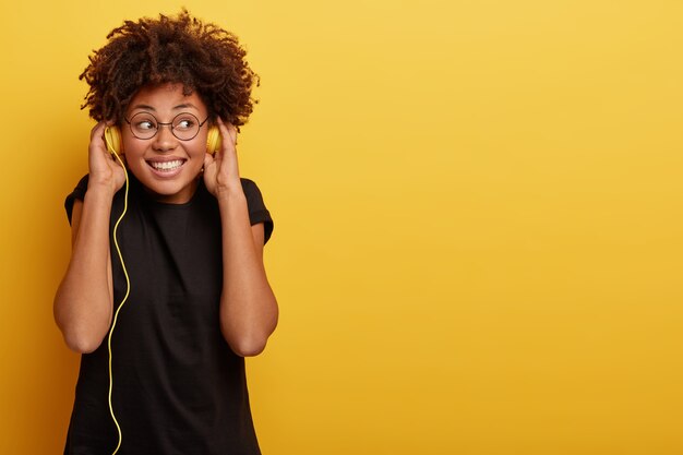 アフロの散髪と黄色のヘッドフォンを持つ若い女性