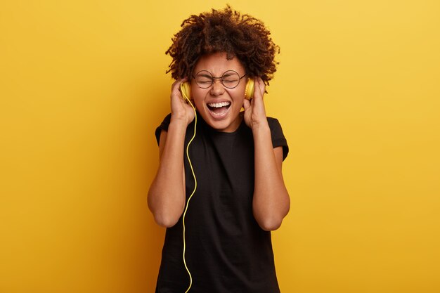 アフロの散髪と黄色のヘッドフォンを持つ若い女性