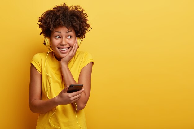 Young woman with Afro haircut and yellow headphones