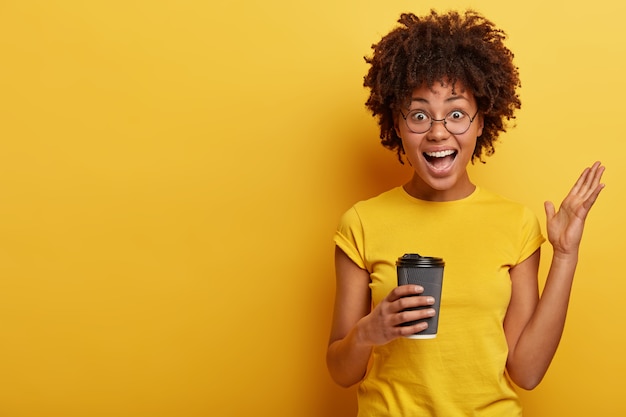 Young woman with Afro haircut and yellow T-shirt holding cup of coffee