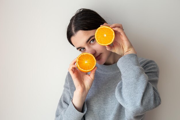 Молодая женщина с аппетитными половинками апельсина на белом фоне
