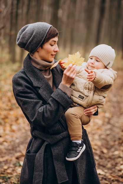 Young woman with baby son walking in autumn park